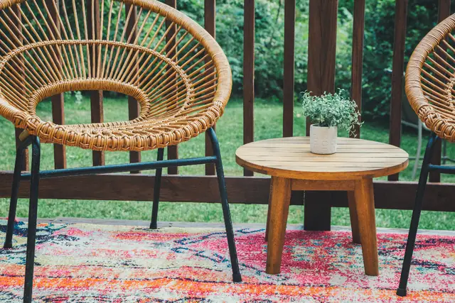 Deck with rattan chairs, a wood table and a red rug