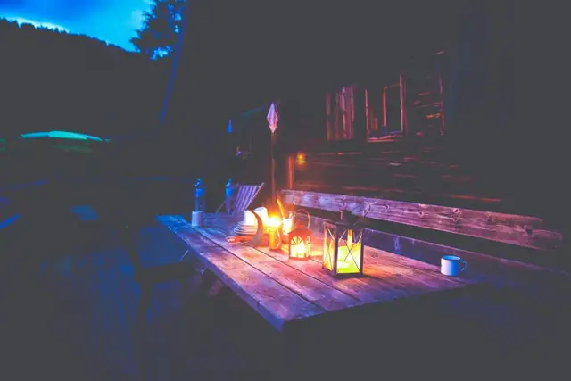 Backyard deck with a picnic table lit by lanterns