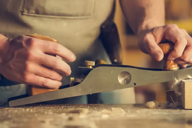 Carpenter's hands using a hand plane on wood