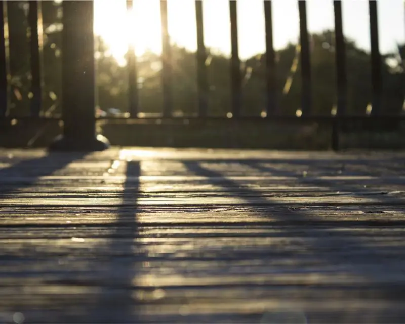 Wooden deck with railing and long shadows at sunset