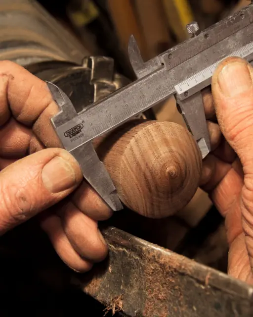 Cal's hands measuring a piece of wood with calipers