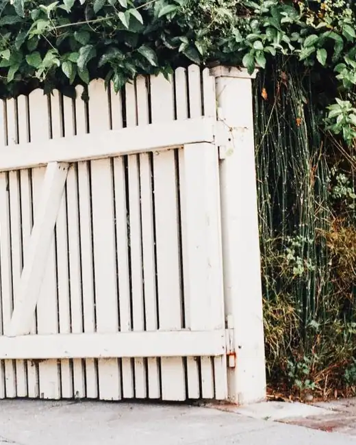 White wooden gate opening into a green yard