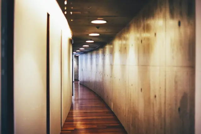Long hallway with warm hardwood floors and wall lights