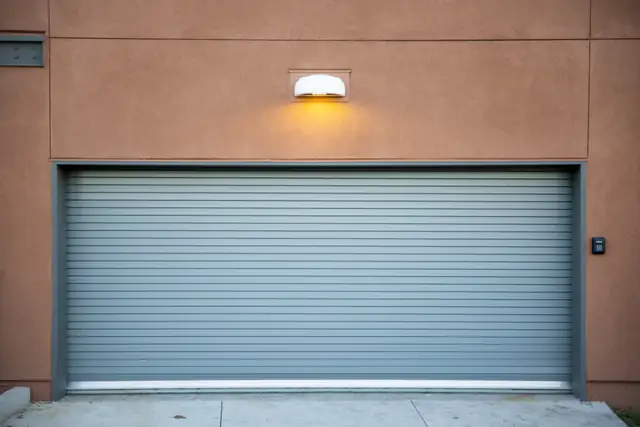 Gray garage door with exterior light on a brick home