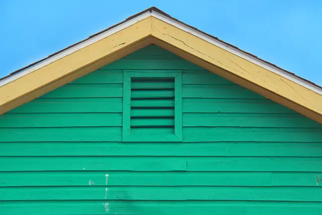 Green siding gable under a blue sky