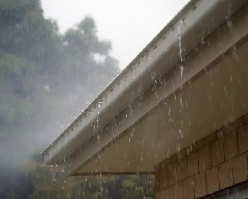 Rainwater pouring over the edge of a gutter