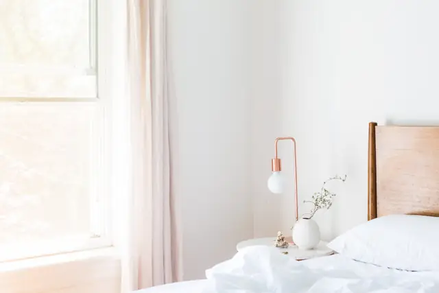 Freshly made white bed by a window