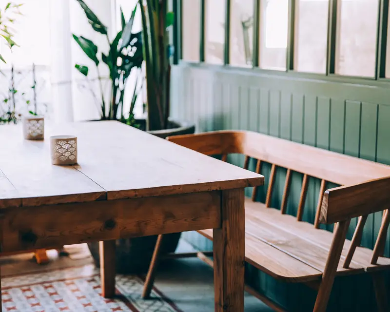 Sunny dining nook with a wood table, bench and plants