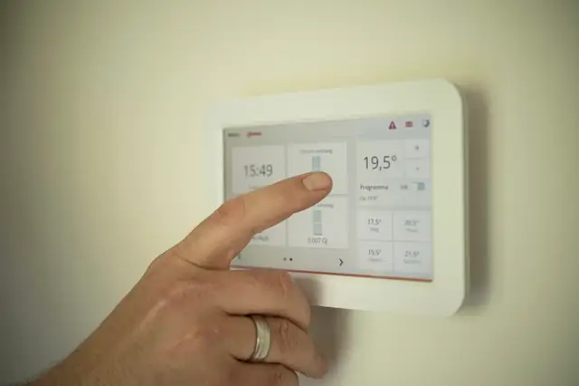 Hand adjusting a digital thermostat