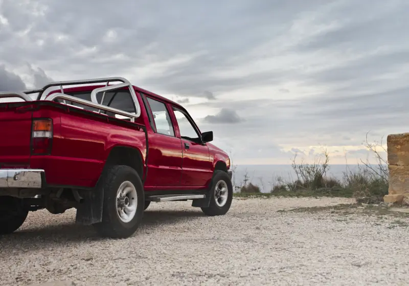 Red pickup truck parked on a gravel lot