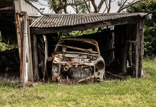 Old wooden shed with a rusted car inside