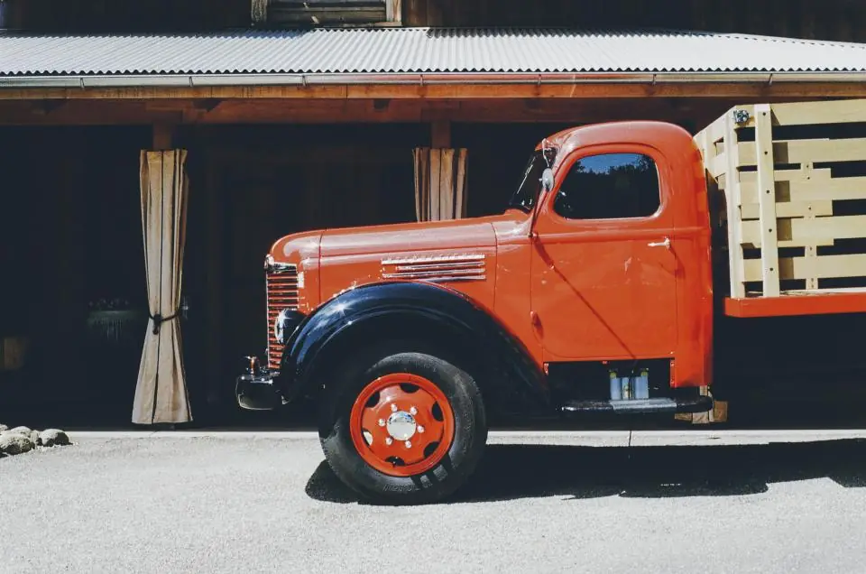 Vintage red flatbed truck parked in front of an open barn