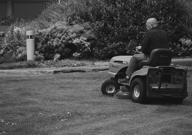 Person riding a mower across a large lawn