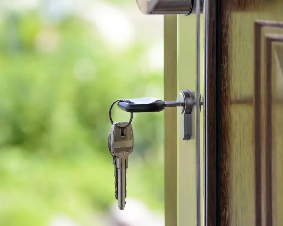 Key turning in the lock of a green front door
