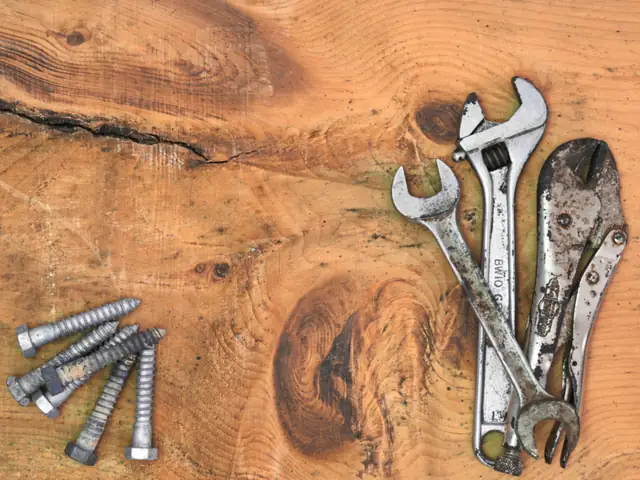 Wrenches and bolts laid out on a wooden bench