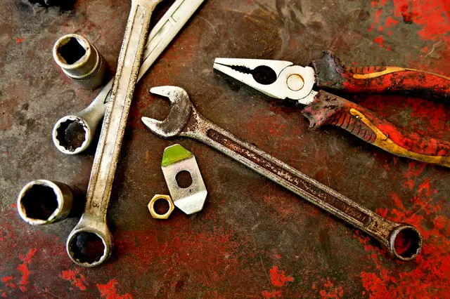 Wrenches, pliers and sockets on a worn surface