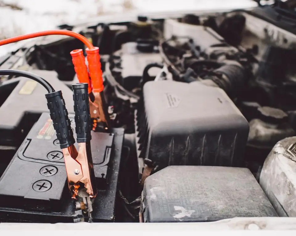 Jumper cables clamped to a car battery under an open hood