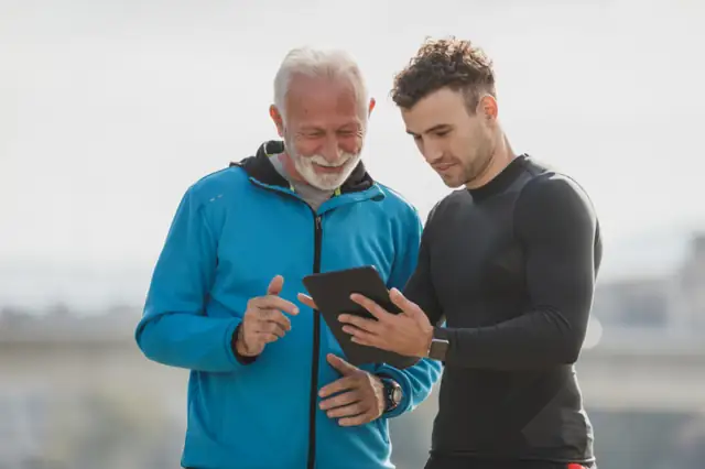 Coach showing an older client his progress on a phone