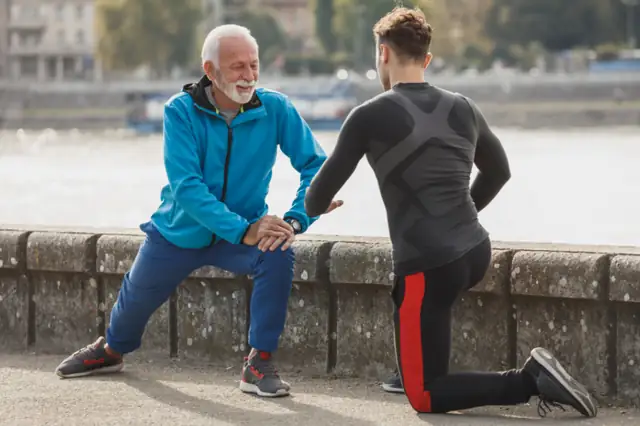 Coach and older client stretching outdoors