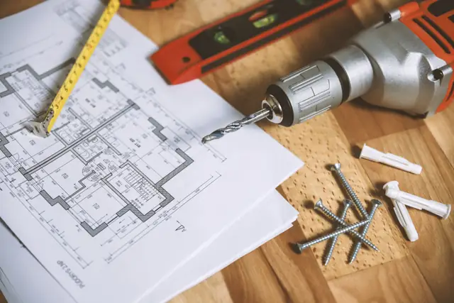 Floor plans, a drill and screws on a work table