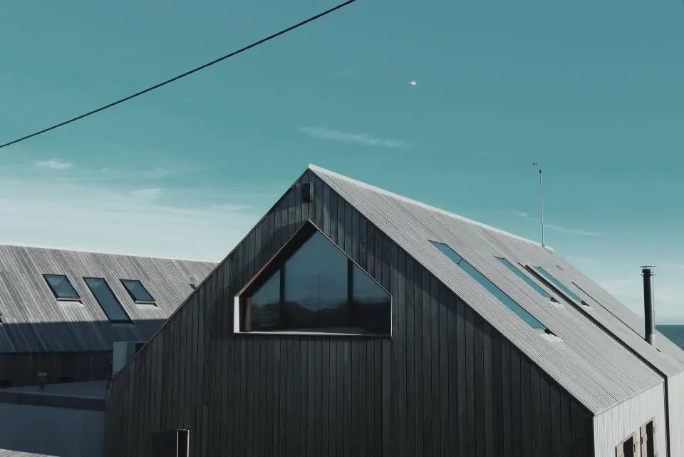 Dark shingle roof of a house against a blue sky