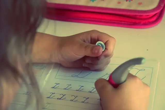 Child's hand writing with a pencil on a worksheet