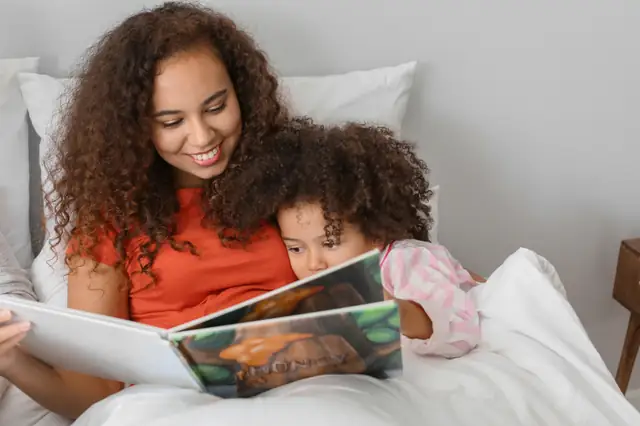 Mother and young daughter reading a book together