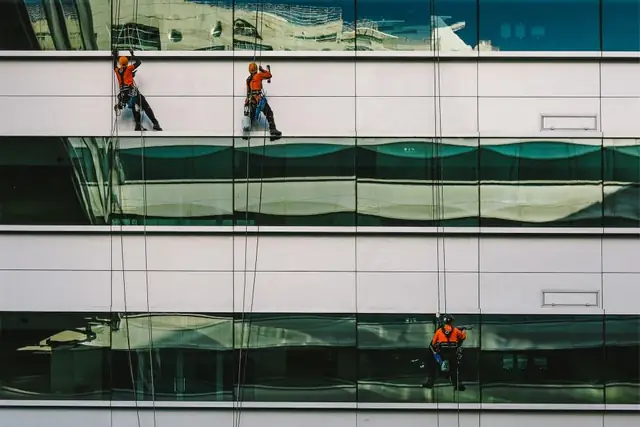 Window cleaners on ropes washing a glass building