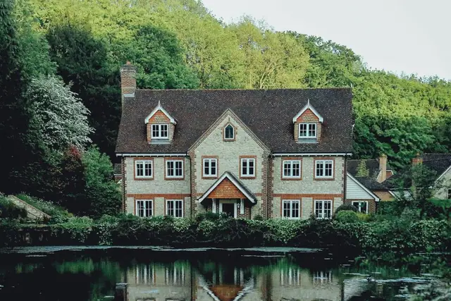 Stone house with many windows by a pond
